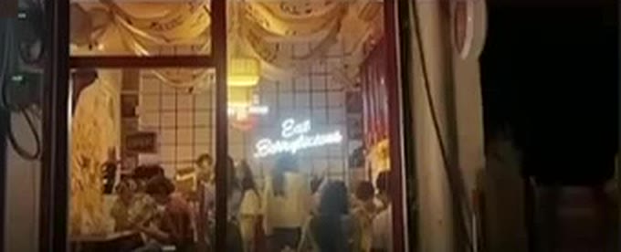 The front of Toku's at night, full of people, with an 'Eat Berrylicious' neon sign