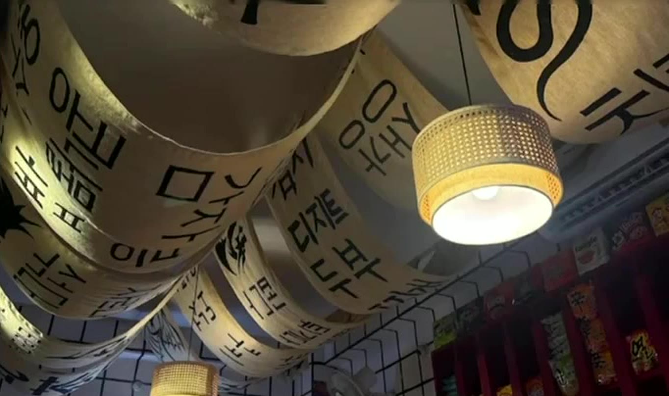 Paper banners printed with Korean letters hanging from the ceiling around a woven lamp